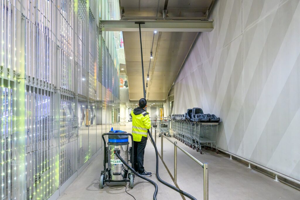 N-Cleanin työntekijä poistaa yläpölyjä kauppakeskuksen tukirakenteesta